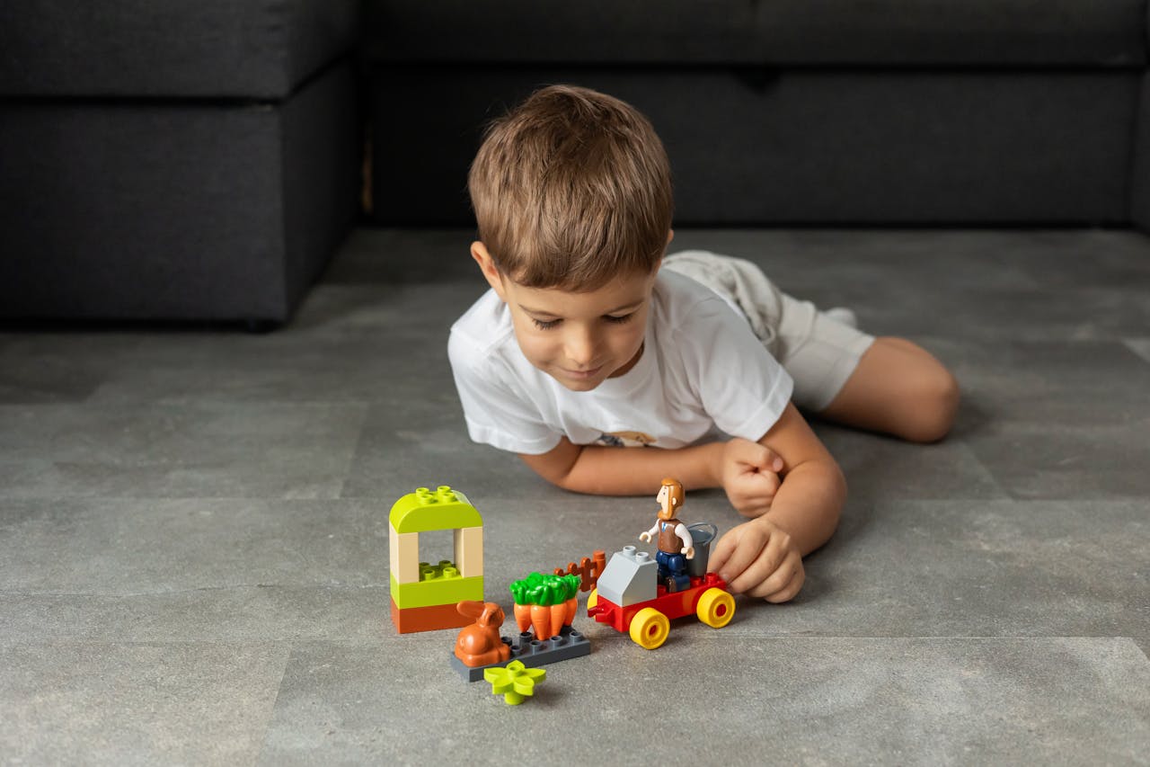 A young boy playing with colorful toy blocks on the floor indoors, enjoying creative playtime.